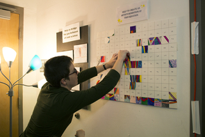 Organizer Hannah Tanquary pins up another segment of the "Equation Art Intervention." The attendees were invited to color a segment of the equation to add to the board. A picture of the completed result can be found on the event's website. (Photo: Mallory Shibe) Organizer Hannah Tanquary pins up another segment of the "Equation Art Intervention." The attendees were invited to color a segment of the equation to add to the board. A picture of the completed result can be found on the event's website. (Photo: Mallory Shibe)