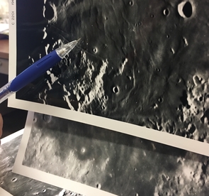 A senior staff scientist who worked for Gerard Kuiper as an undergraduate points to the Apollo 11 landing site on photos from the Consolidated Lunar Atlas. The top photo was taken with the sun at a low angle, which reveals more detail than the bottom photo, which was taken with the sun overhead. (Photo: Mikayla Mace/UANews) A senior staff scientist who worked for Gerard Kuiper as an undergraduate points to the Apollo 11 landing site on photos from the Consolidated Lunar Atlas. The top photo was taken with the sun at a low angle, which reveals more detail than the bottom photo, which was taken with the sun overhead. (Photo: Mikayla Mace/UANews)