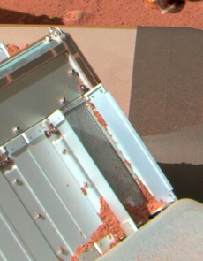The UA-built Thermal and Evolved Gas Analyzer, or TEGA, in action on the surface of Mars. An open door has received a sample of Martian dirt delivered by the robotic arm scoop while an adjacent set of closed doors is awaiting its sample delivery. In the foreground is a corner of the box housing the mass spectrometer that was used to analyze the Martian atmosphere. The UA-built Thermal and Evolved Gas Analyzer, or TEGA, in action on the surface of Mars. An open door has received a sample of Martian dirt delivered by the robotic arm scoop while an adjacent set of closed doors is awaiting its sample delivery. In the foreground is a corner of the box housing the mass spectrometer that was used to analyze the Martian atmosphere.