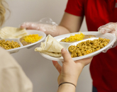 Volunteers' hands passing two full plates of chorizo and eggs. (Photo: Kyle Mittan/University Communications)