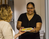 A volunteer passing a full plate of chorizo and eggs to another person. (Photo: Kyle Mittan/University Communications)