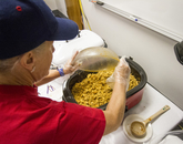 A volunteer pouring a bowl of chorizo and eggs into a slow cooker. (Photo: Kyle Mittan/University Communications)