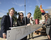Five attendees stand next to a white steel beam decorated with signatures. From left: Gregg Goldman, UA senior vice president for business affairs and chief financial officer; Aundrea DeGravina and Vianney Careaga, student members of the Arizona Board of Regents; Richard H. Silverman, vice chair of the UA Foundation board of trustees and of counsel at Jennings, Strouss & Salmon PLC; and Lyndel Manson, regent. (Kris Hanning/UAHS BioCommunications)