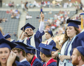Jesus Gaurdado of Los Angeles, who graduated with a degree in accounting, waves so that his family can find him amid a sea of blue robes in Arizona Stadium. (Photo: John de Dios/UANews) Jesus Gaurdado of Los Angeles, who graduated with a degree in accounting, waves so that his family can find him amid a sea of blue robes in Arizona Stadium. (Photo: John de Dios/UANews)