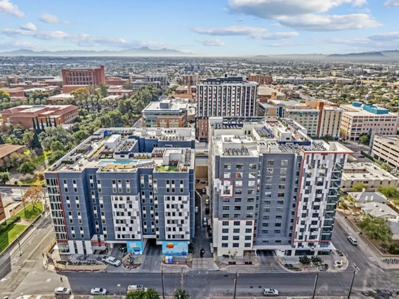 Aerial view of modern mid-rise apartment buildings in an urban area, surrounded by city streets and other commercial and residential buildings.