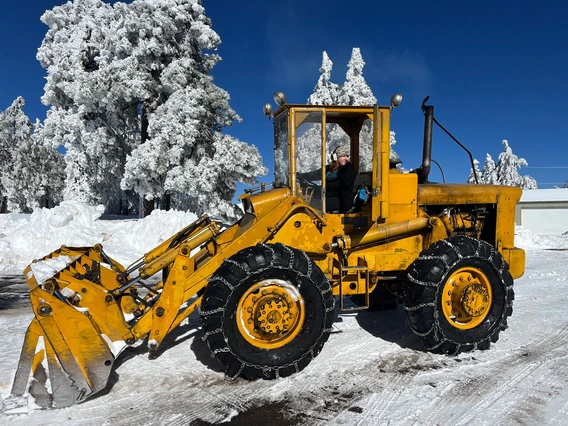 Alyson Ford is pictured driving a yellow front loader with snow chains