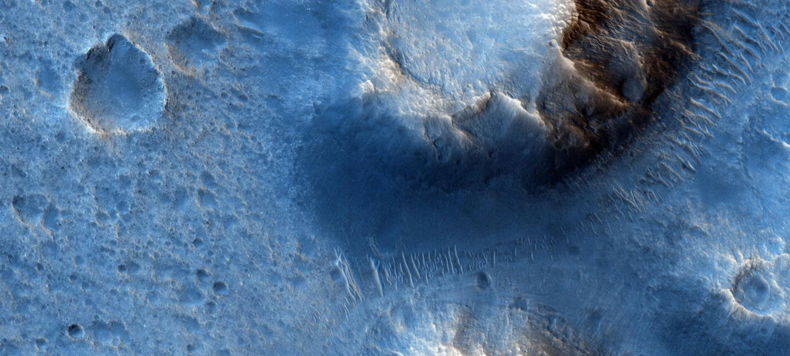 If the two crater- or volcano-like features dominating this HiRISE image are indeed ancient volcanoes, the blue color would indicate basalt, a telltale sign of having a volcanic origin. This image is about half a mile across.