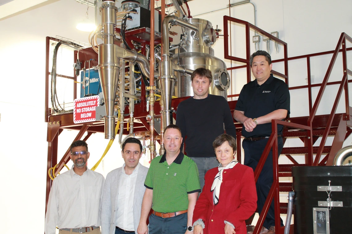 The Mach-X research team posing for a photo in their lab with scientific machinery behind them