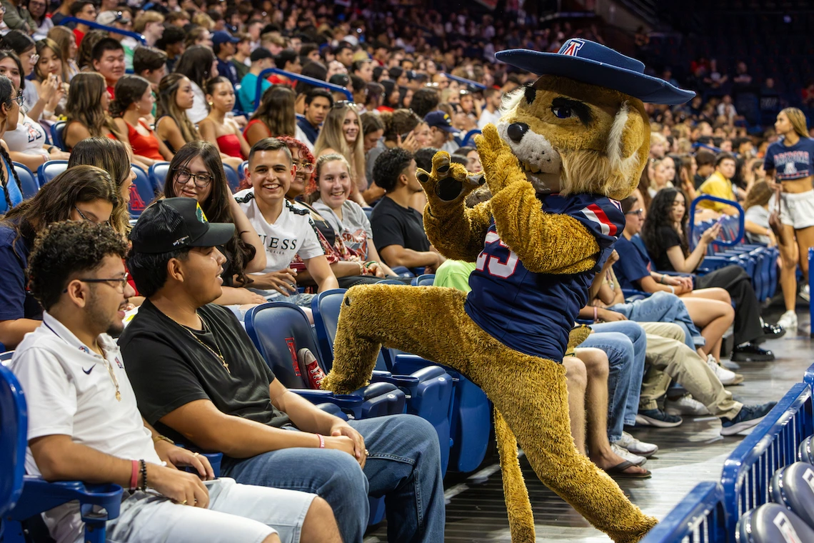 Wilbur Wildcat, the University of Arizona mascot, playfully poses in the stands with cheering students during the Destination Arizona event.