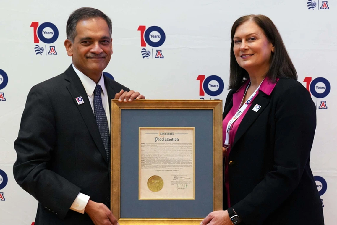 A man and a woman stand holding a plaque.