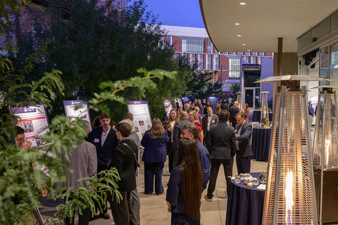 Several people gather at a reception in a courtyard outside the Andrew Weil Center for Integrative Medicine