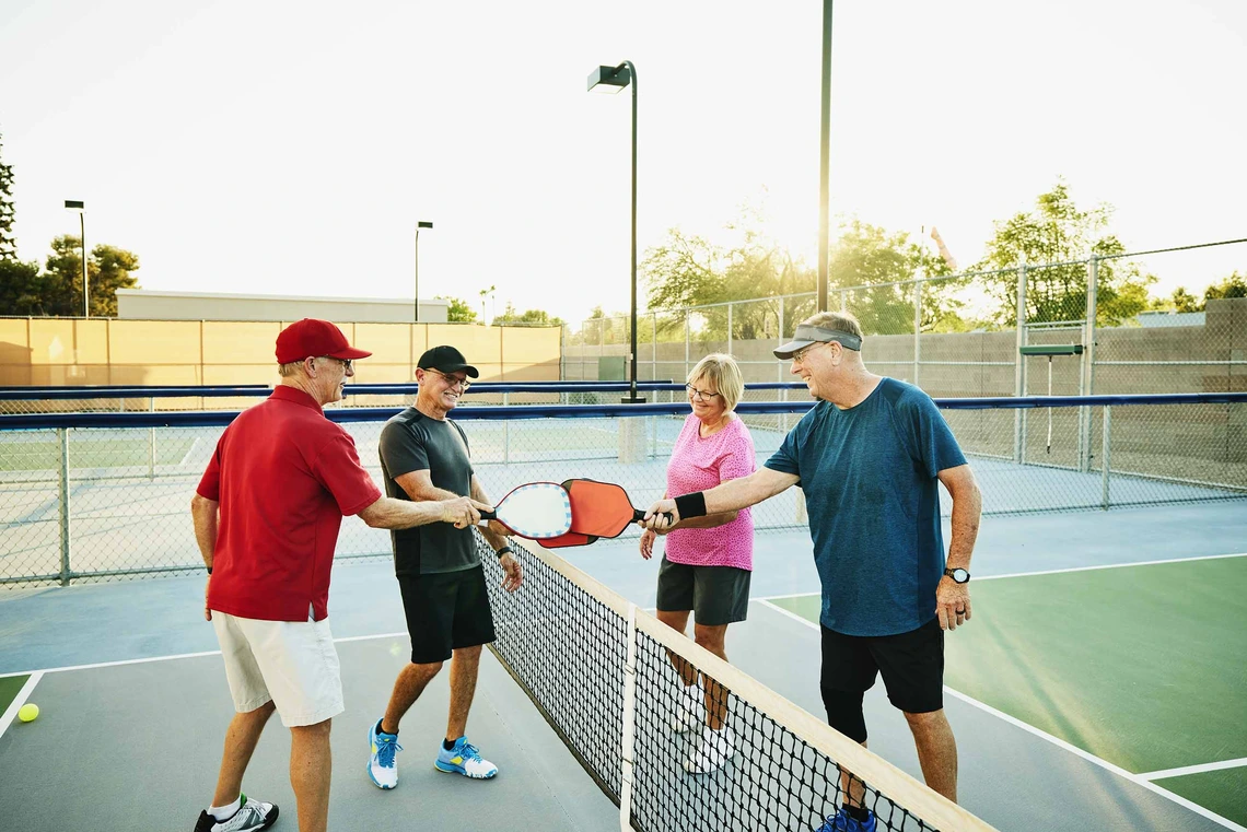 Four older people playing pickleball