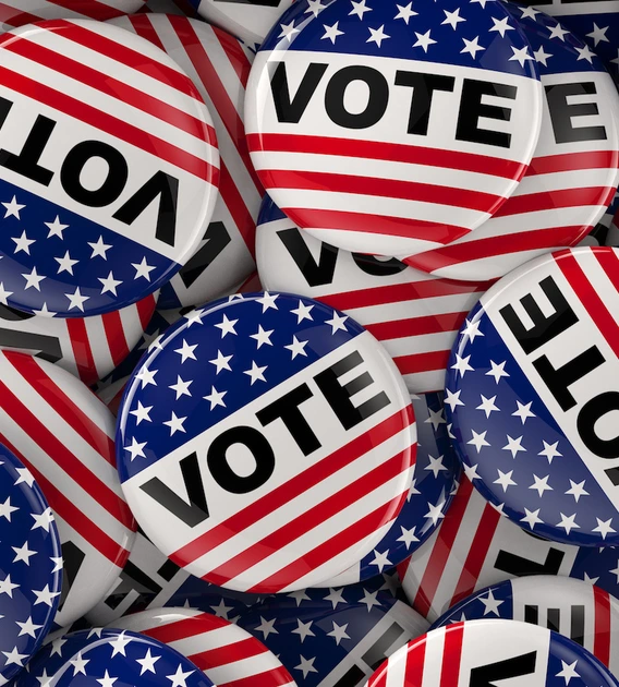 A pile of red, white, and blue "VOTE" buttons featuring stars and stripes, designed to resemble the American flag.