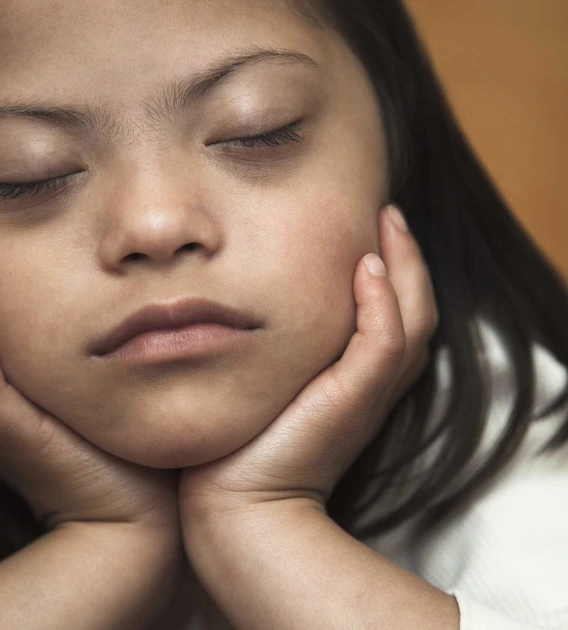 a girl with her eyes closed with her chin resting in her hands
