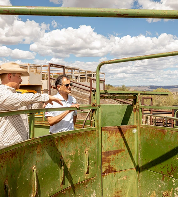 Two men examine agricultural equipment at a ranch.