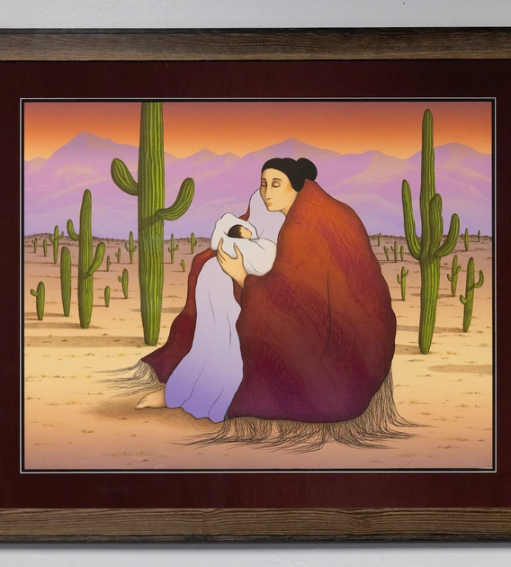 a photo of a lithograph in a frame showing a Native American woman holding a swaddled baby in the desert surrounded by saguaros