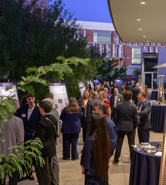 Several people gather at a reception in a courtyard outside the Andrew Weil Center for Integrative Medicine