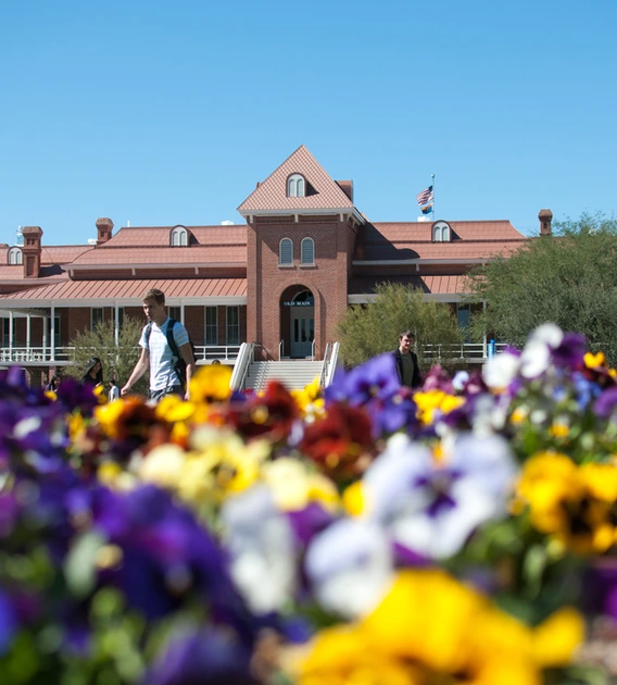 Old Main in the background, with purple, yellow, white and red flowers in the foreground