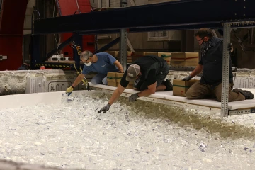 Engineers at the Richard F. Caris Mirror Lab hand-load chunks of glass into the mold of the spinning furnace.  