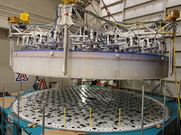 The Rubin Observatory's Primary/Tertiary Mirror (M1M3) is lifted into its transport/storage container using a custom vacuum lift.