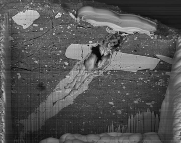 A scanning electron microscope image of a micrometeorite impact crater in a particle of asteroid Bennu material.