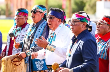 Hopi men singing and gesturing, with some holding traditional percussive instruments