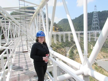 Alyson Ford standing on the walkway surrounding the dish of the FAST radio telescope