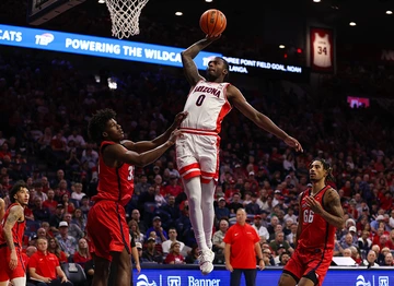 Men's basketball player Jaden Bradley rises for a slam dunk