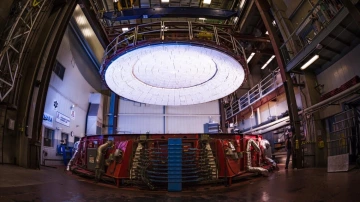a large mirror lid suspended over a rotating furnace Glass is melted inside a rotating furnace, shown here with the lid suspended from an overhead crane. (Photo by: Damien Jemison/GMTO Corp.)