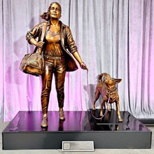 A bronze statue of a woman and a dog mounted on a black pedestal.