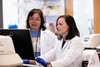 Zelieann Craig looking at a computer monitor in a lab while wearing a lab coat