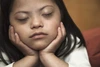 a girl with her eyes closed with her chin resting in her hands