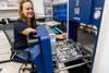 Jessica Barnes sitting in a chair in her lab, loading a sample into an analyzer instrument