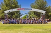 Several college students throw their caps into the air under an archway with the words Arizona Wildcats on it.