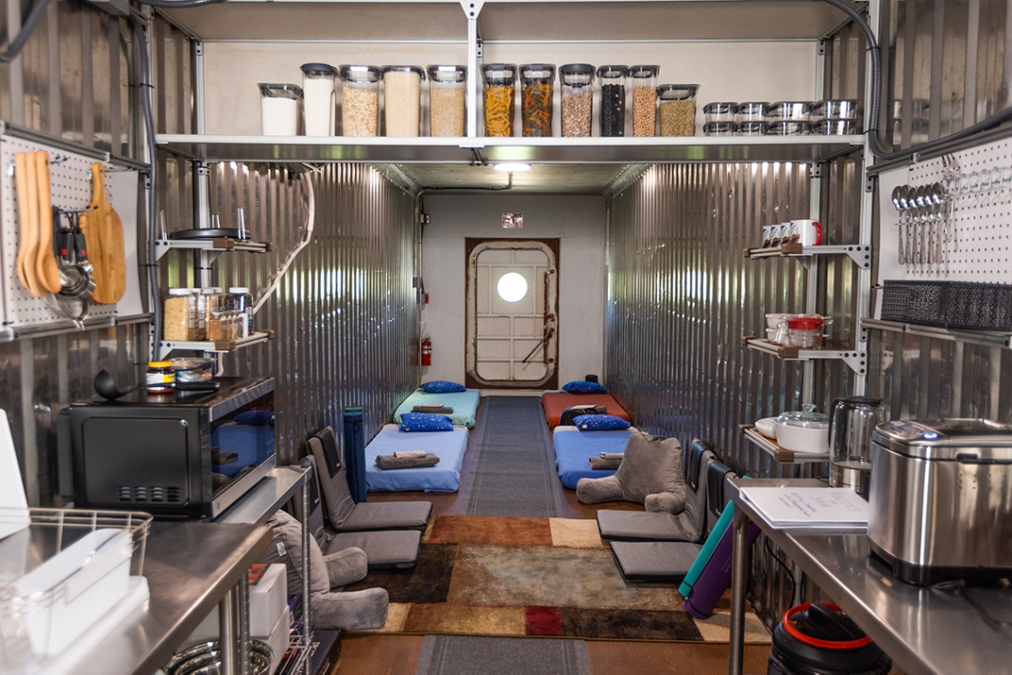 The interior of the crew's habitat containing a kitchen area and floor futons.