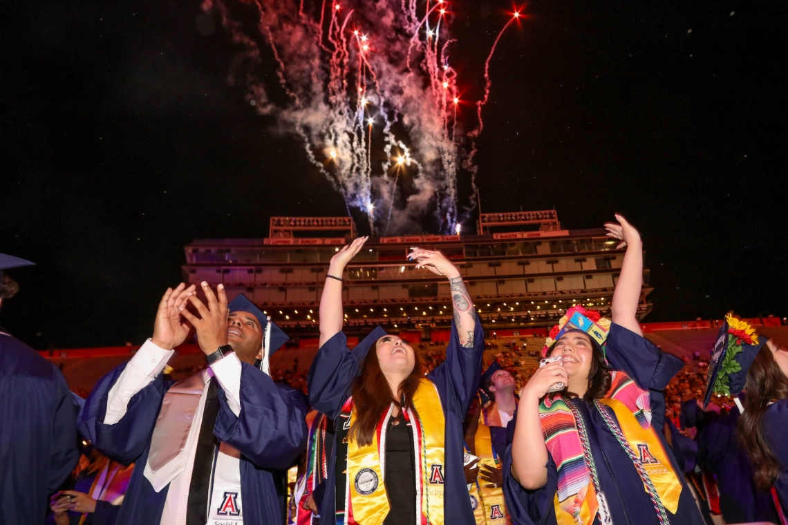 students celebrating during a fireworks display at commencement