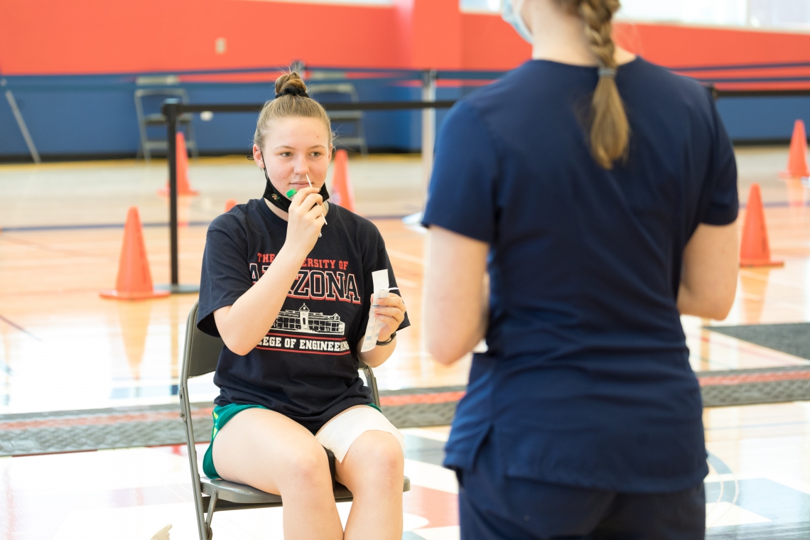 a female student self-administers a nasal swab antigen test