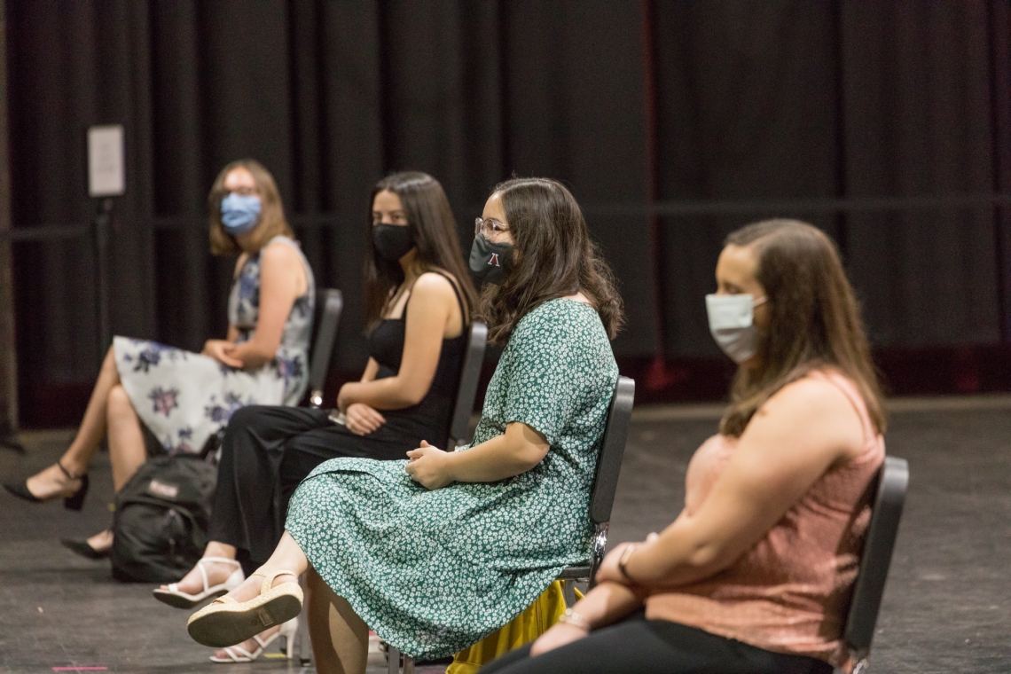 four female students wearing masks, seated spaced apart