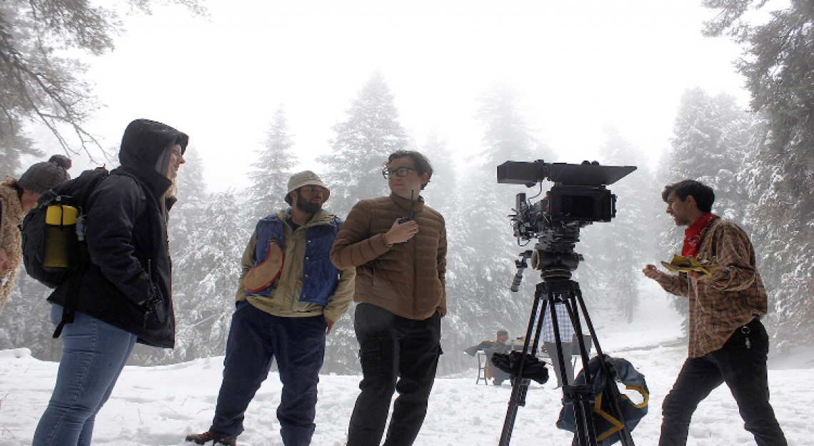 a group of people in a snowy field with filmmaking equipment