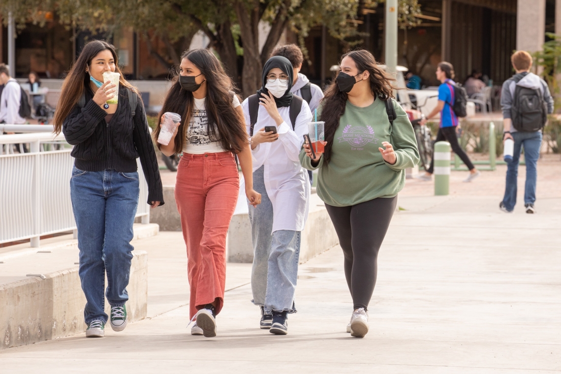 four female students wearing masks and walking on campus