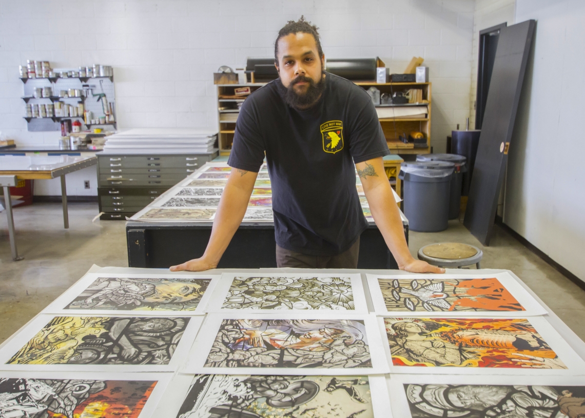 Aaron Coleman with some of his work at the UA School of Art's print shop. (Photo by Kyle Mittan/University Communications) aaron coleman with several prints