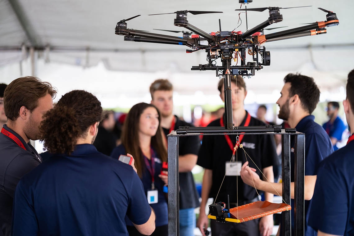 people standing under a tent while demonstrating a robotic system for exploring Mars