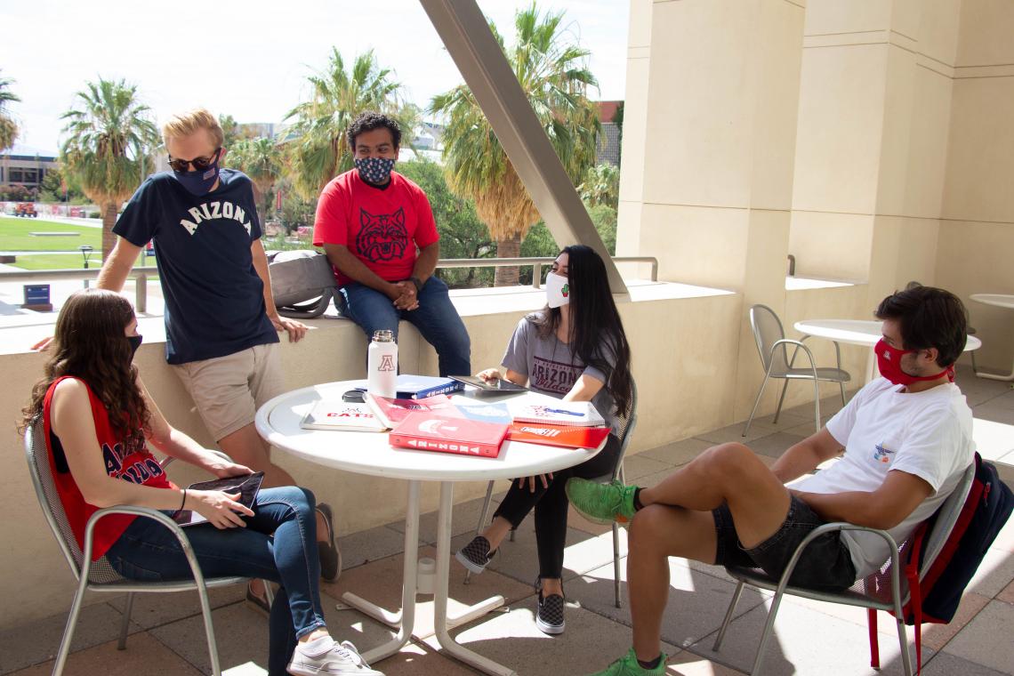 students wearing masks gathered around a table at the Student Union
