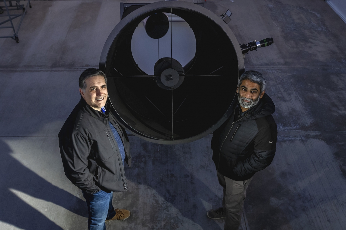 two people standing near a telescope