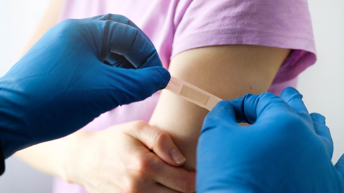 A person wearing blue medical gloves applies a bandage to someone's arm. A person wearing blue medical gloves applies a bandage to someone's arm.