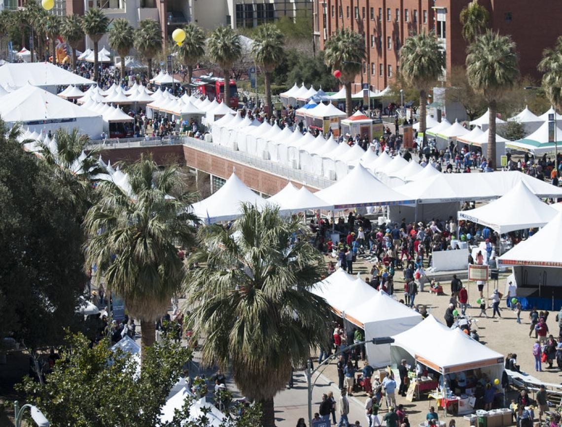 several white tents and a crowd of people on the university of arizona campus