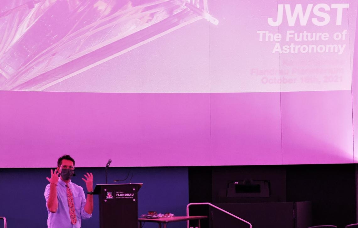 man speaking in front of a large pink screen