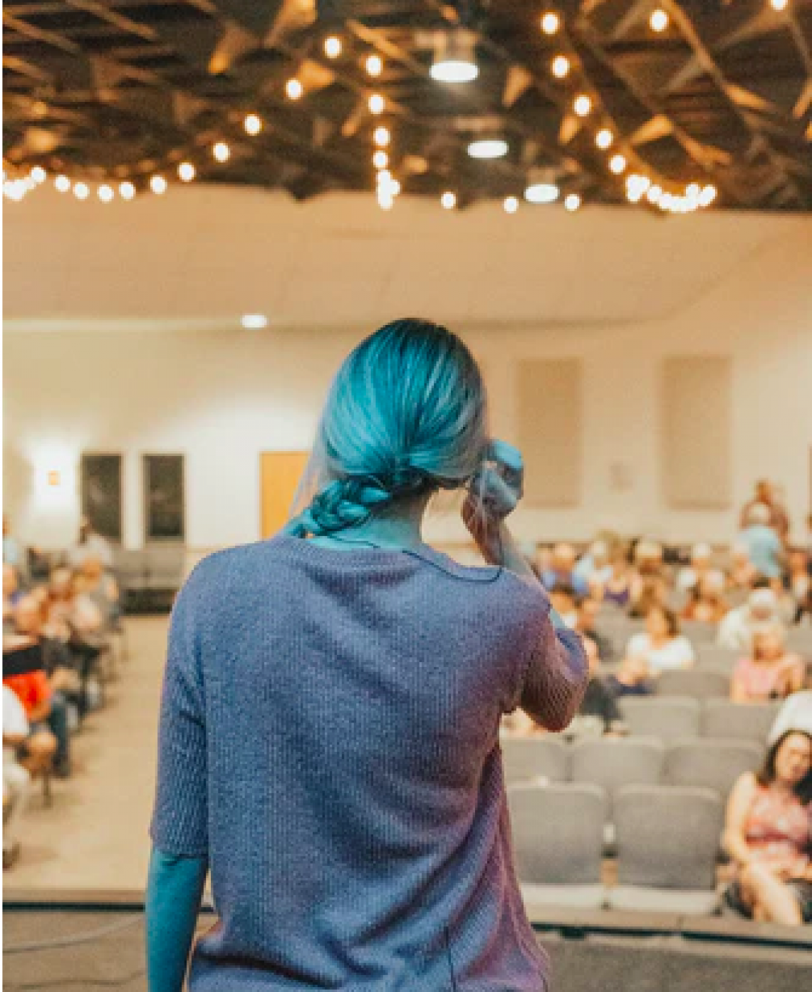 Lecturer with their back to the camera facing a hall of students