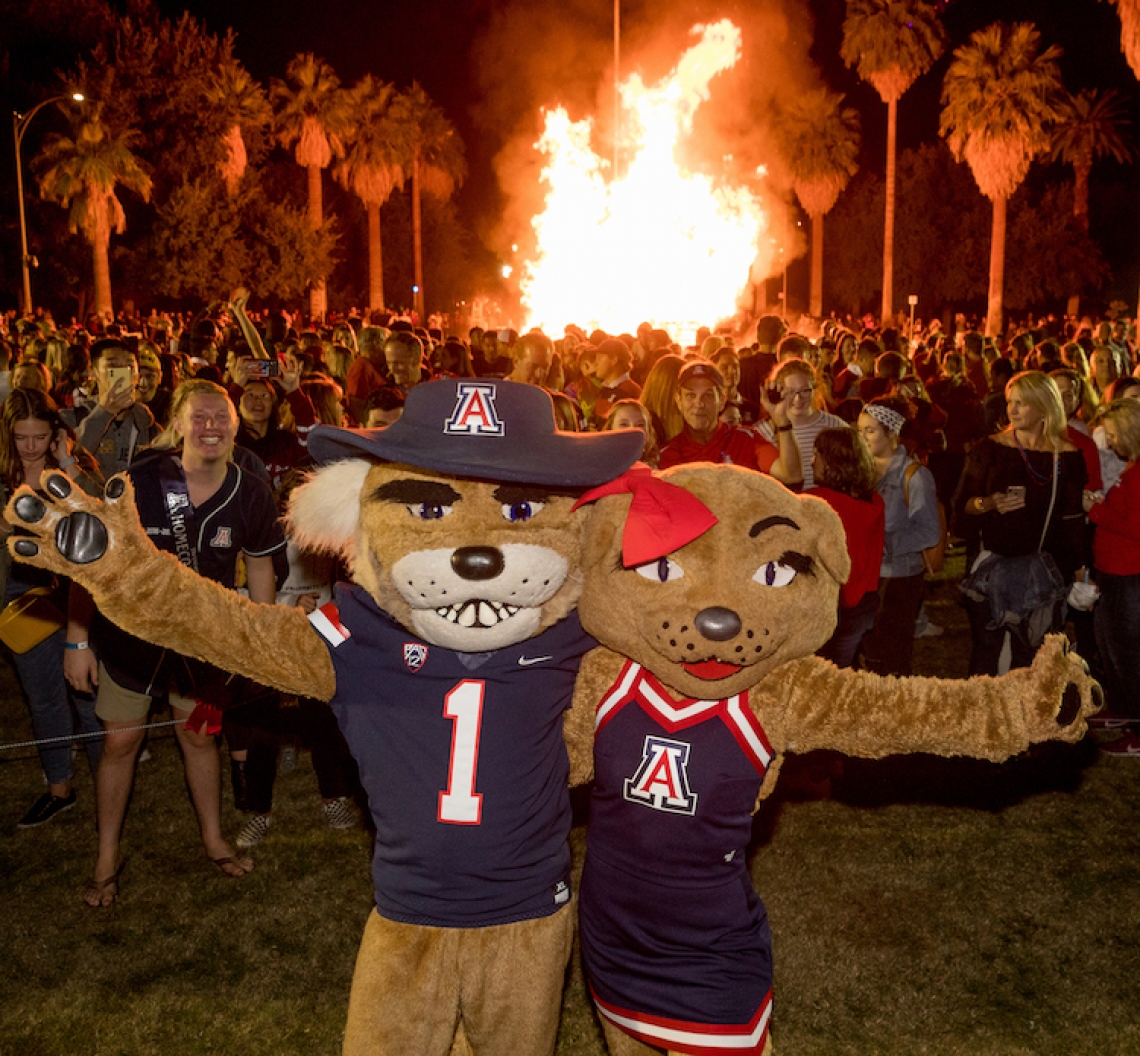 wilbur and wilma wildcat in front of a large group of students and a bonfire