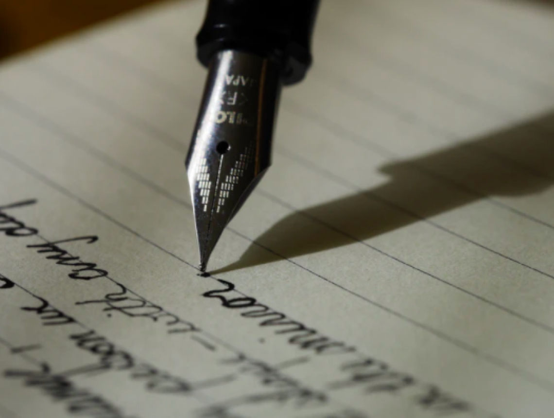 Close up image of a fountain pen writing on lined notebook paper